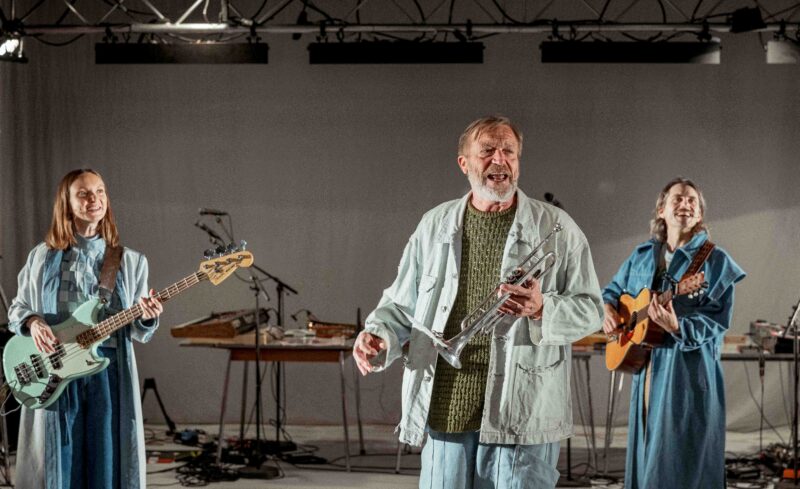 Tre personer synger. Alle har et instrument hver