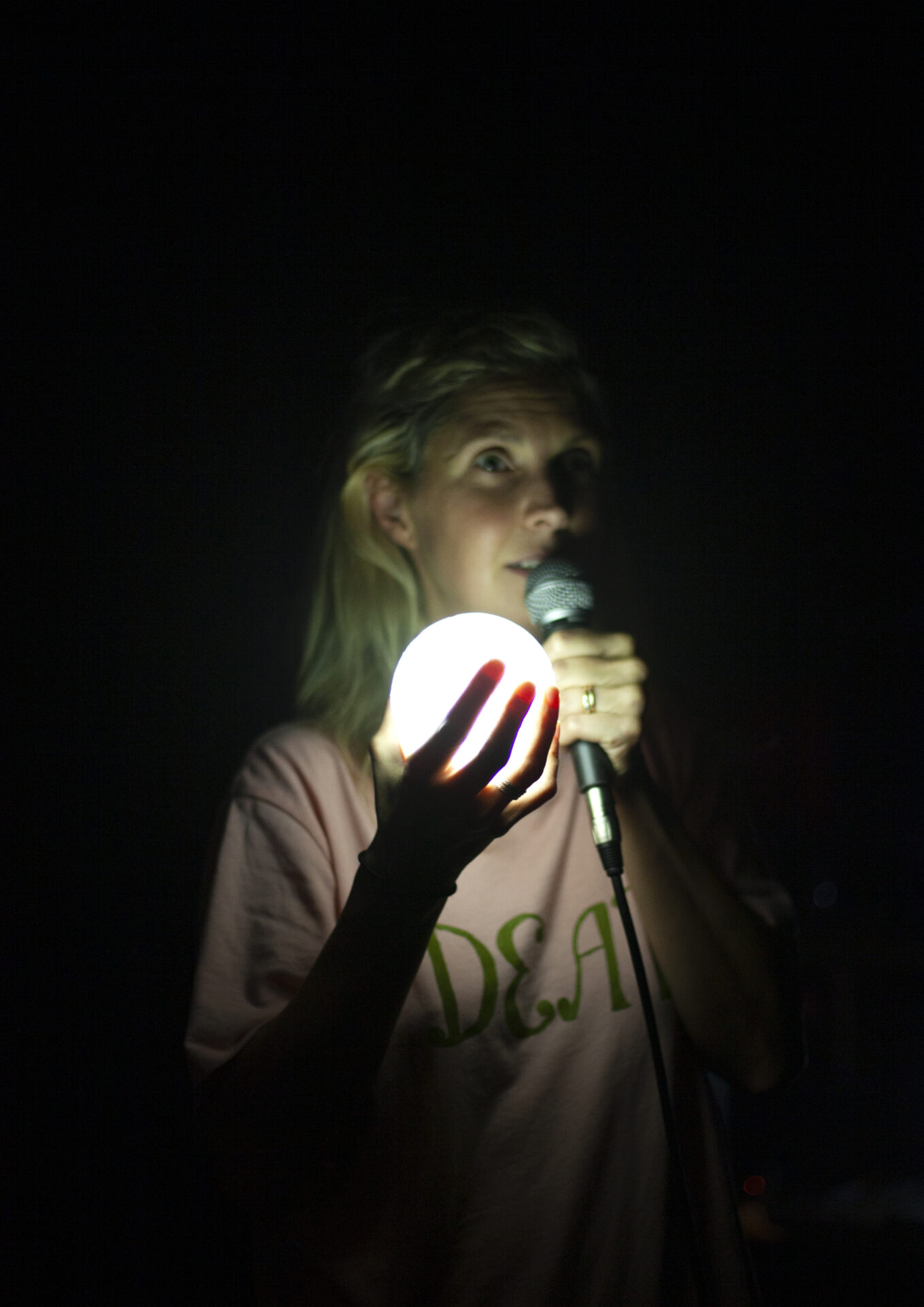 Kvinne med mikrofon holder lysende kule