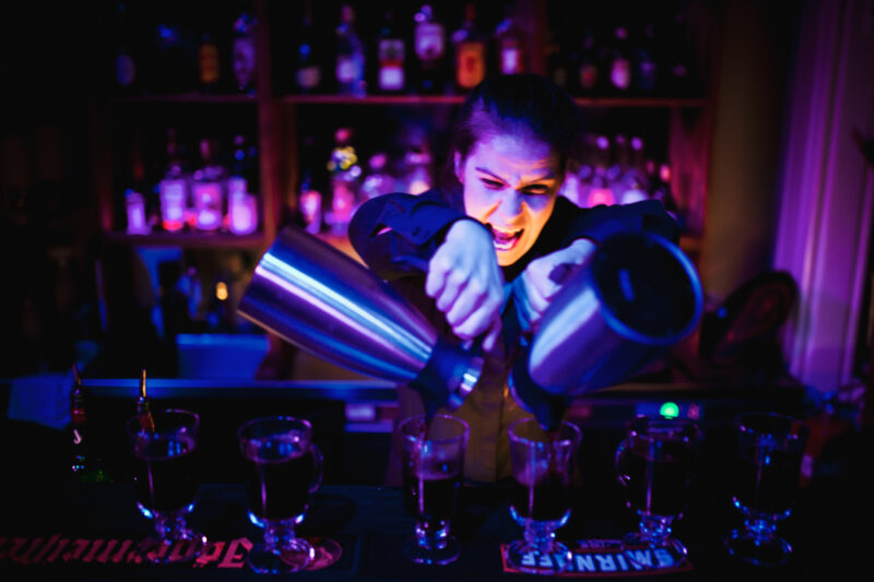 Person står bak en bardisk og heller i drikke i to glass