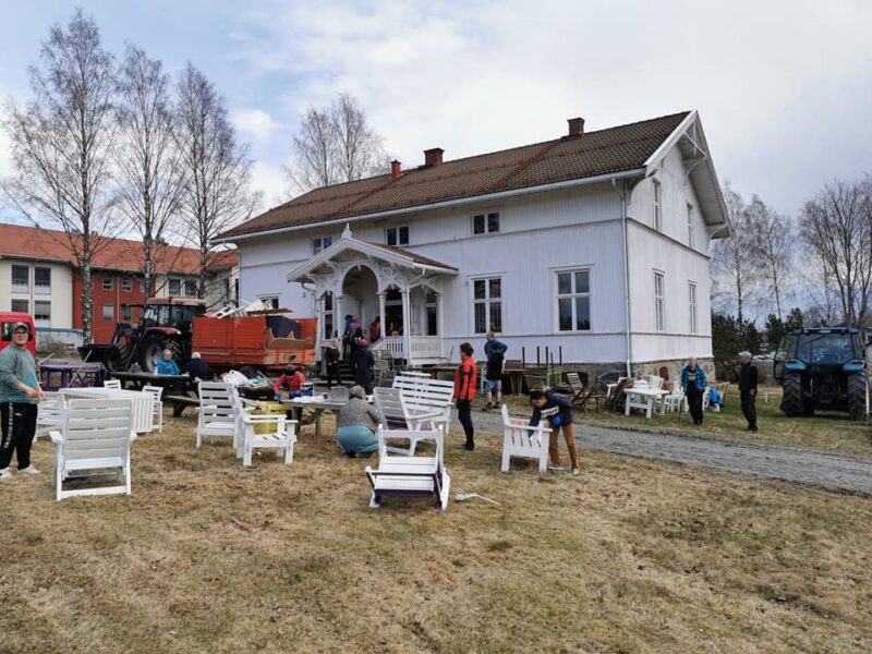 Hus med folk og stoler foran