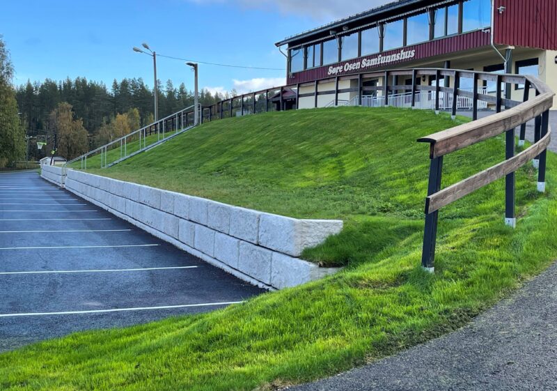 Deler av en parkeringsplass, og et hus på toppen av en bakke