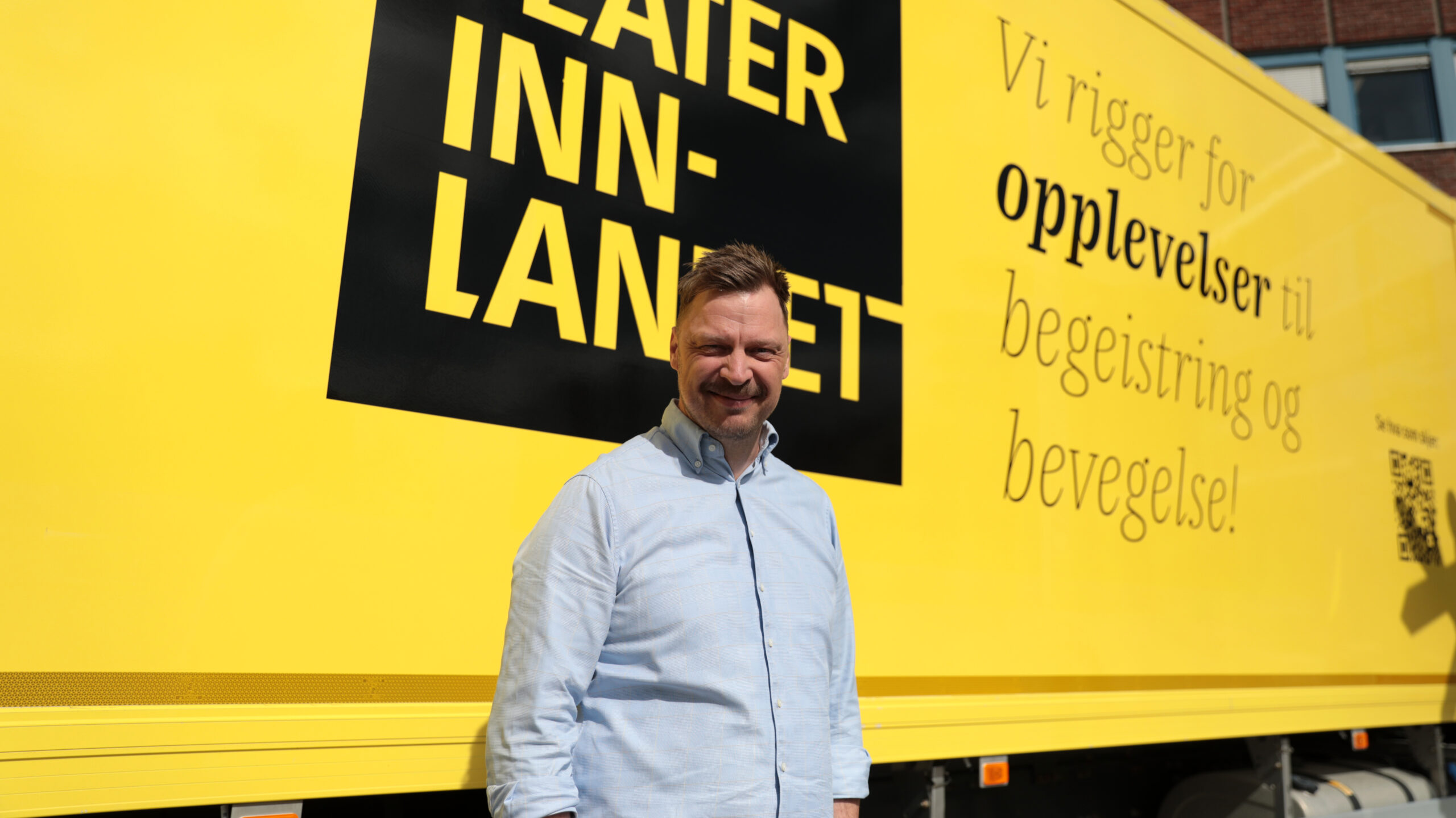 En mann står foran en gul lastebil
