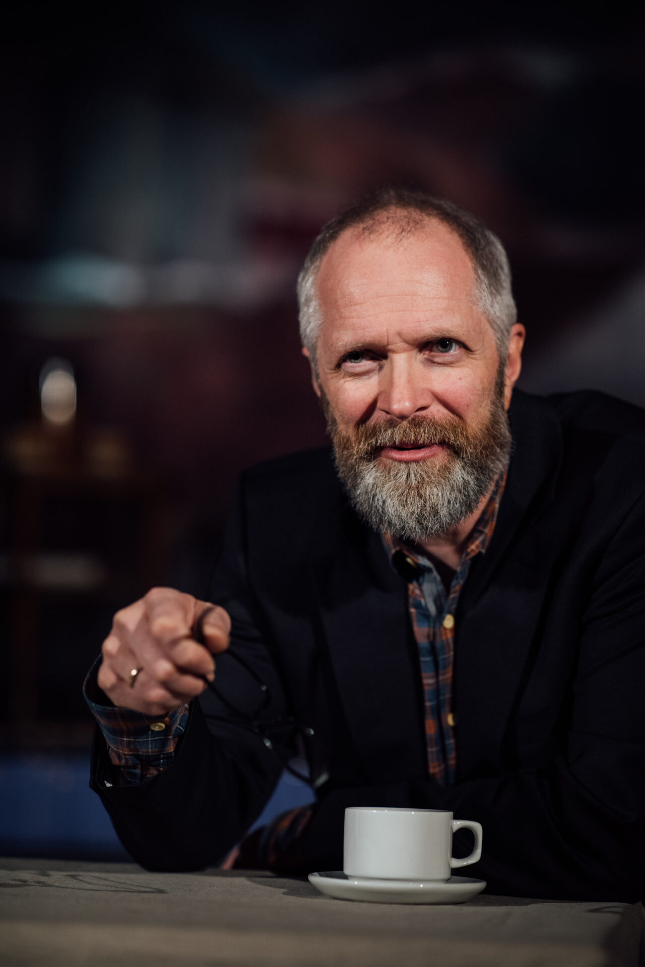 En mann med rutete skjorte og dressjakke peker