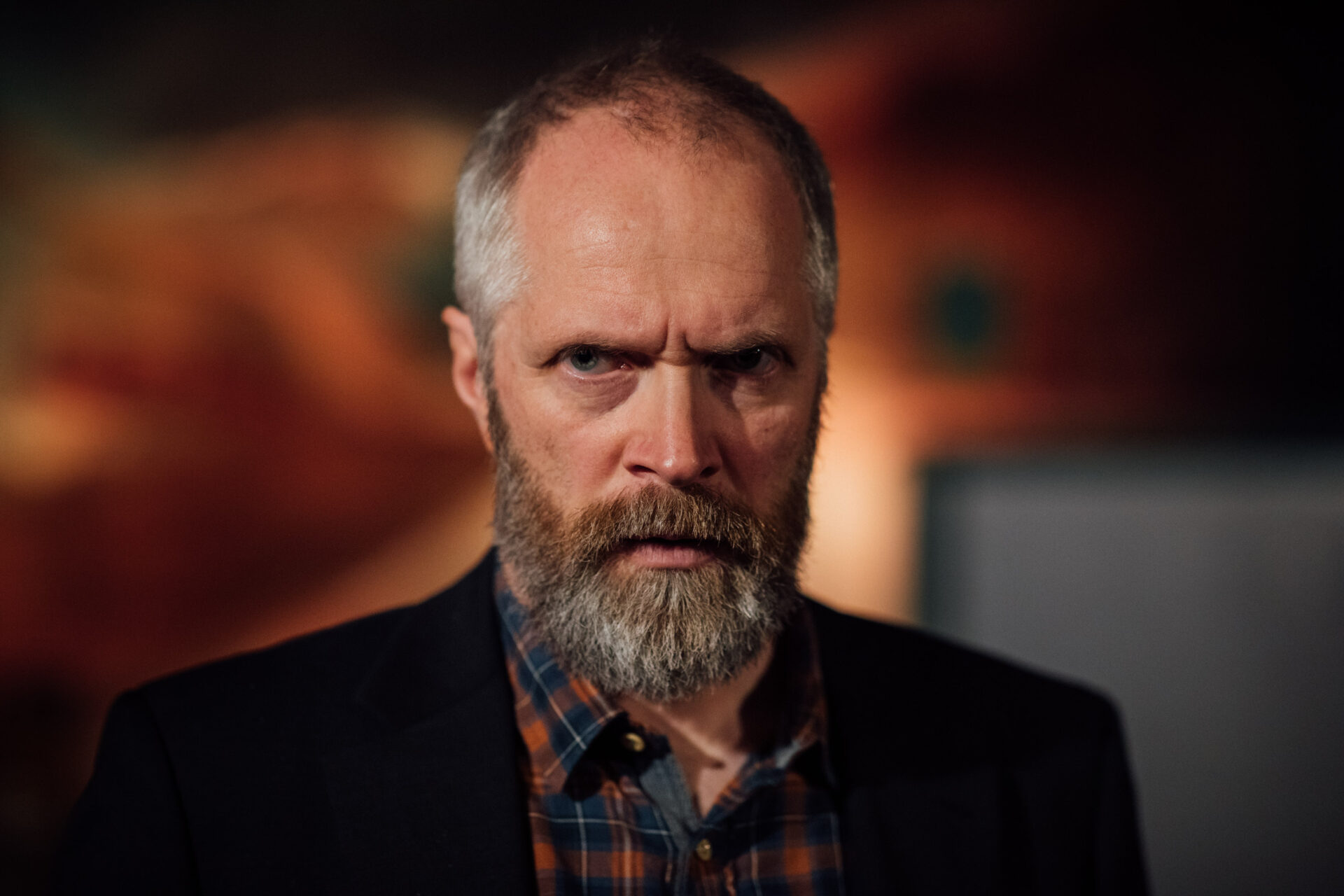 En mann med rutete skjorte og dressjakke