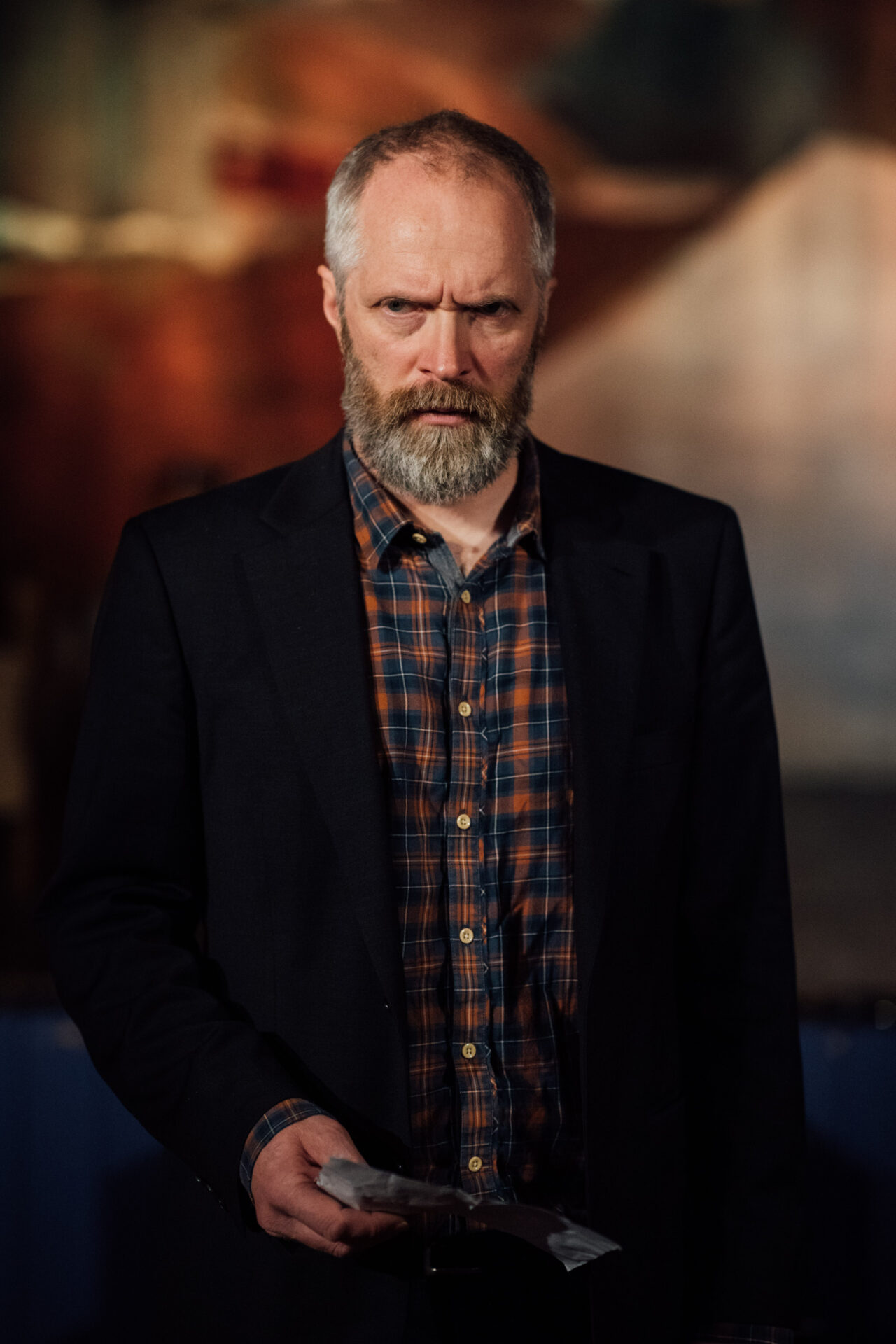 En mann med rutete skjorte og dressjakke