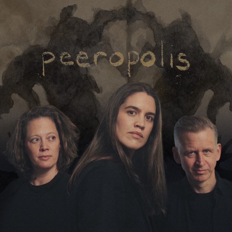 En kvinne står foran en annen kvinne og en mann. De står bak, på hver sin side av kvinnen i front