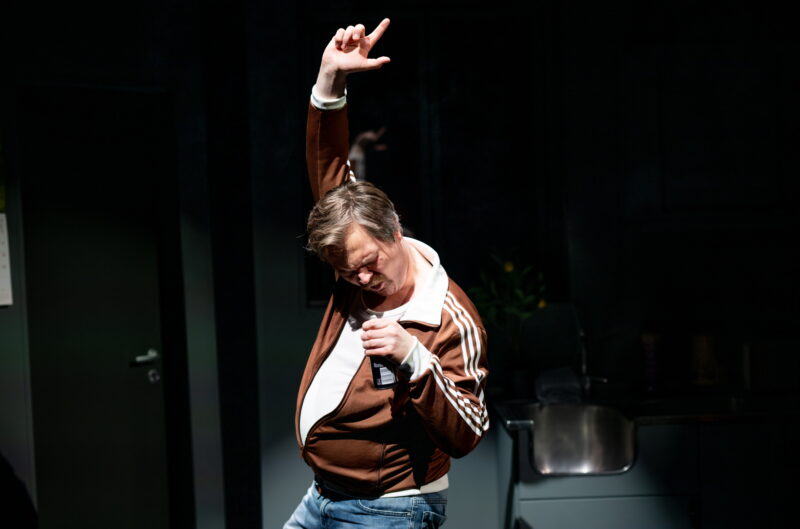 En mann danser, med den ene hånden i været og en brusboks i den andre og holder den som om det var en mikrofon.